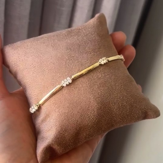 Pulseira dourada com pontos de luz em almofada